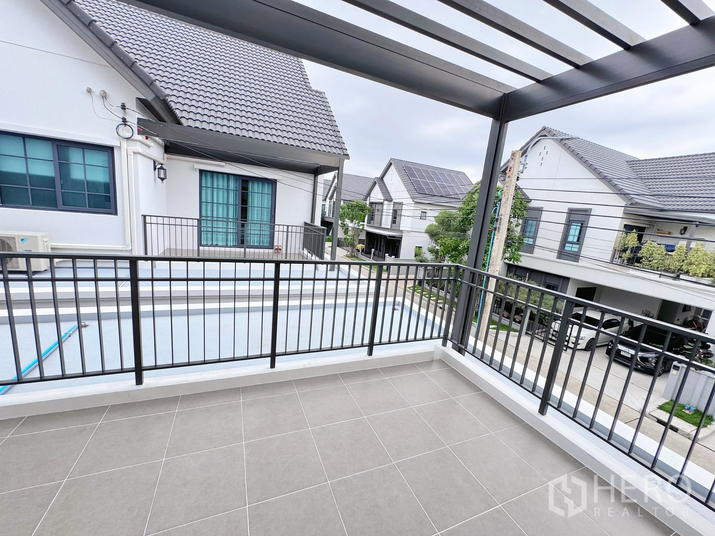 Detached House for rent in Bang Phli, Samut Prakan - Covered balcony with tiled floor and metal railing overlooking neighborhood homes.