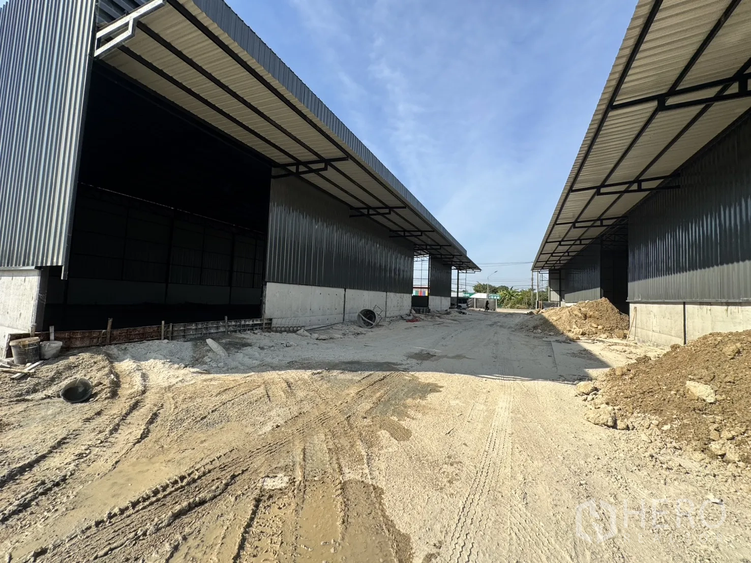 Warehouse for rent in Lam Luk Ka, Pathum Thani - Driveway between two warehouse rows featuring deep eaves and spacious loading bays.