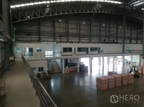 Warehouse for rent in Nong Chok, Bangkok - Spacious warehouse interior featuring a high steel truss roof, mezzanine offices, and polished concrete floor.