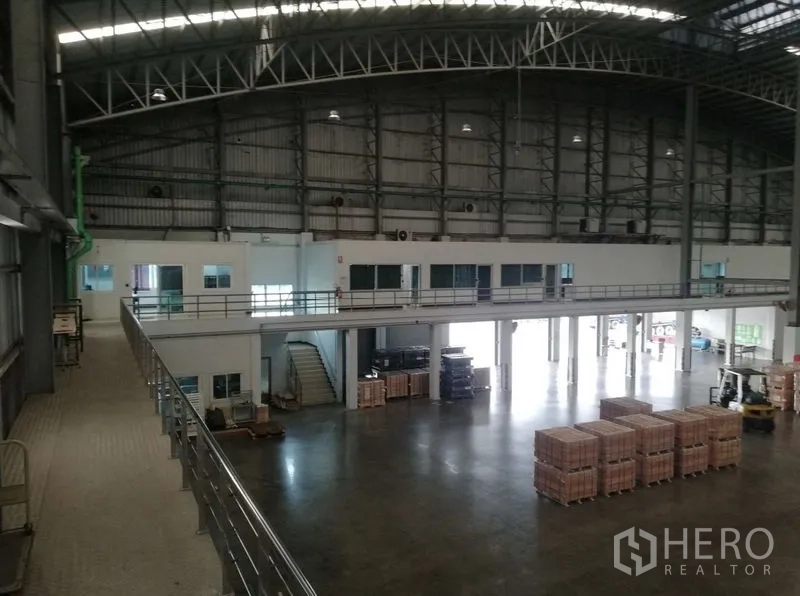 Warehouse for rent in Nong Chok, Bangkok - Spacious warehouse interior featuring a high steel truss roof, mezzanine offices, and polished concrete floor.
