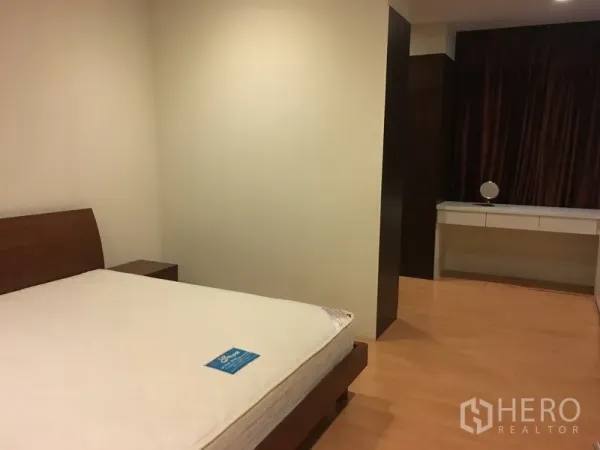 Condominium for rent in Khlong Toei, Bangkok - Second bedroom with wood flooring, platform bed, and built-in dressing area.