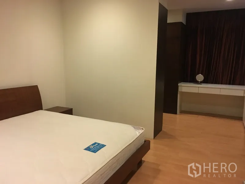 Condominium for rent in Khlong Toei, Bangkok - Second bedroom with wood flooring, platform bed, and built-in dressing area.