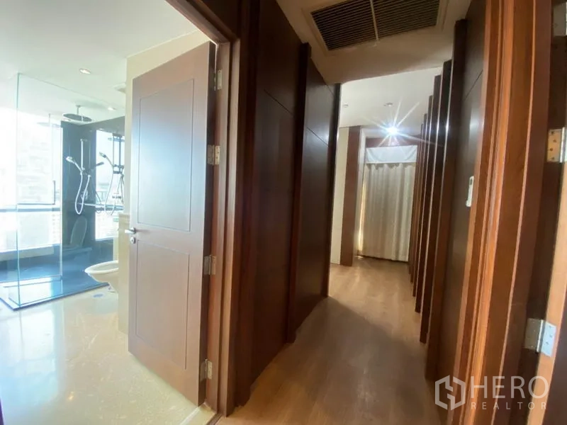 公寓 出租在Sathon, Bangkok - 木质走廊通向明亮浴室，设玻璃淋浴间。