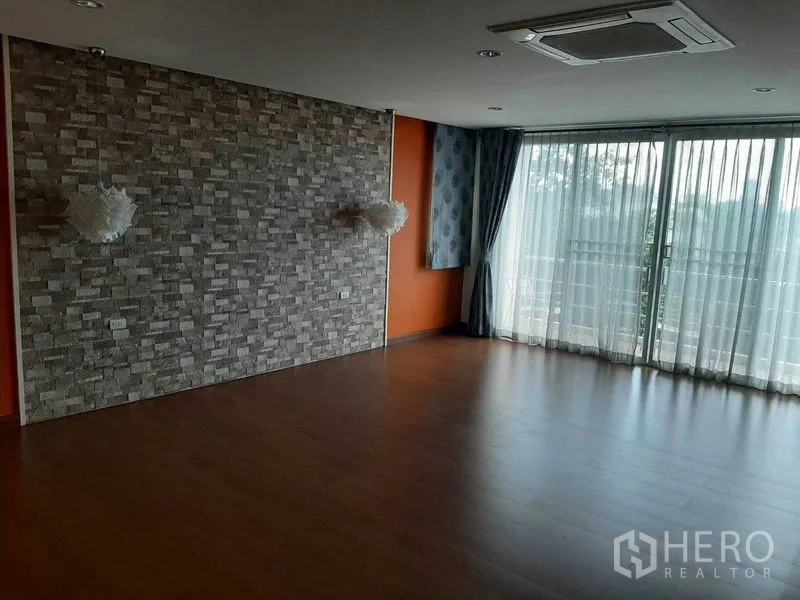 Home Office for sale in Phra Khanong, Bangkok - Open living space with stone accent wall, wood floors and sliding glass doors.