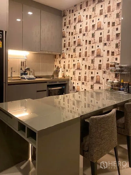 Condominium for rent in Bang Rak, Bangkok - Compact kitchen with glossy cabinets, built-in oven, and a large breakfast island.