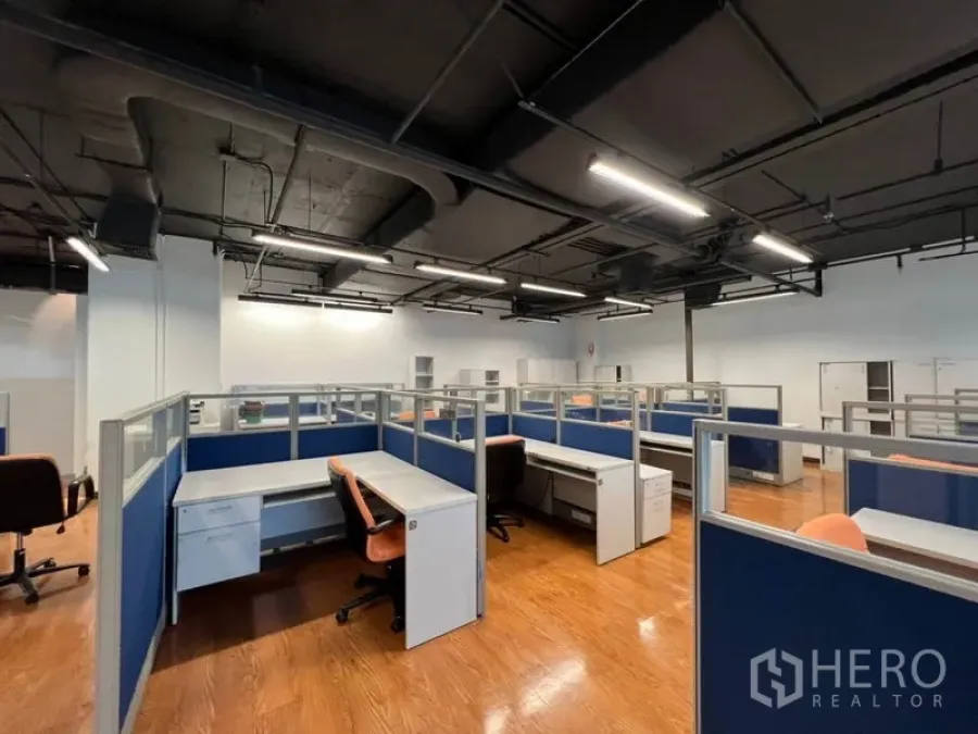 Office Space for rent in Khlong Toei, Bangkok - Open-plan office with blue cubicles, wood floors, exposed black ceiling and linear LED lighting.