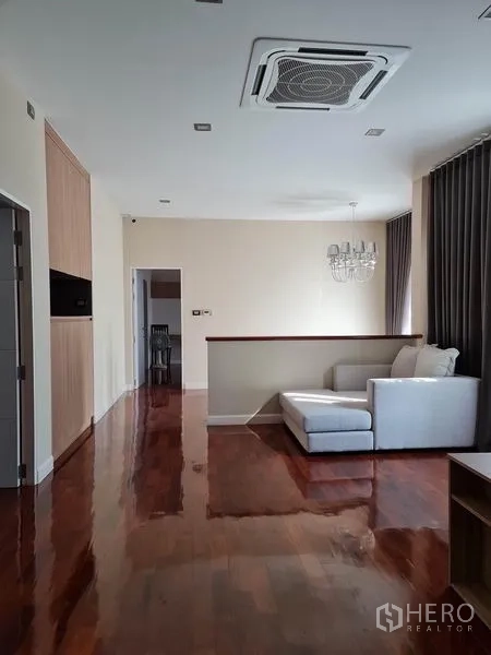 独立式住宅 出售在Khlong Toei, Bangkok - 二楼起居区，木地板，L形沙发，水晶吊灯，大窗与吊顶空调。