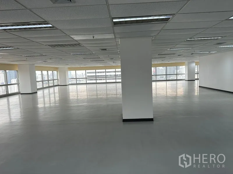 Office Space for rent - Unfurnished office with a central column and large end windows bringing in natural light.