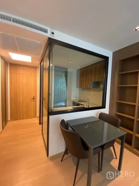 公寓 出租在Watthana, Bangkok - 紧凑餐区，靠玻璃隔断的厨房与高书架