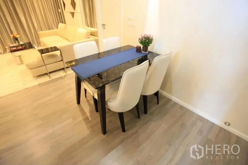 Condominium for rent or sale in Watthana, Bangkok - Compact dining set with two white chairs and dark stone tabletop on wood floor.