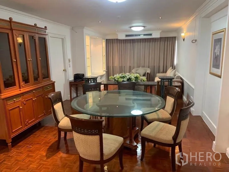 คอนโด ขายในWatthana, Bangkok - พื้นที่นั่งเล่นและรับประทานอาหารแบบเปิด พร้อมโต๊ะกินข้าวกระจกทรงกลม ตู้ไม้สไตล์คลาสสิก และพื้นปาร์เกต์กับผ้าม่านทึบ