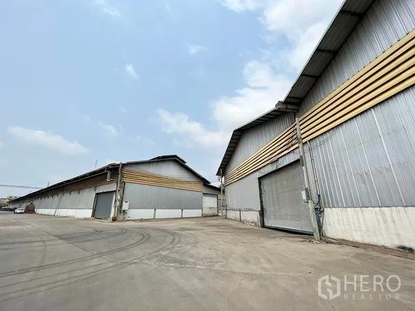 Warehouse for rent in Phra Samut Chedi, Samut Prakan - Row of warehouses with shutter doors and wide turning area for trucks.