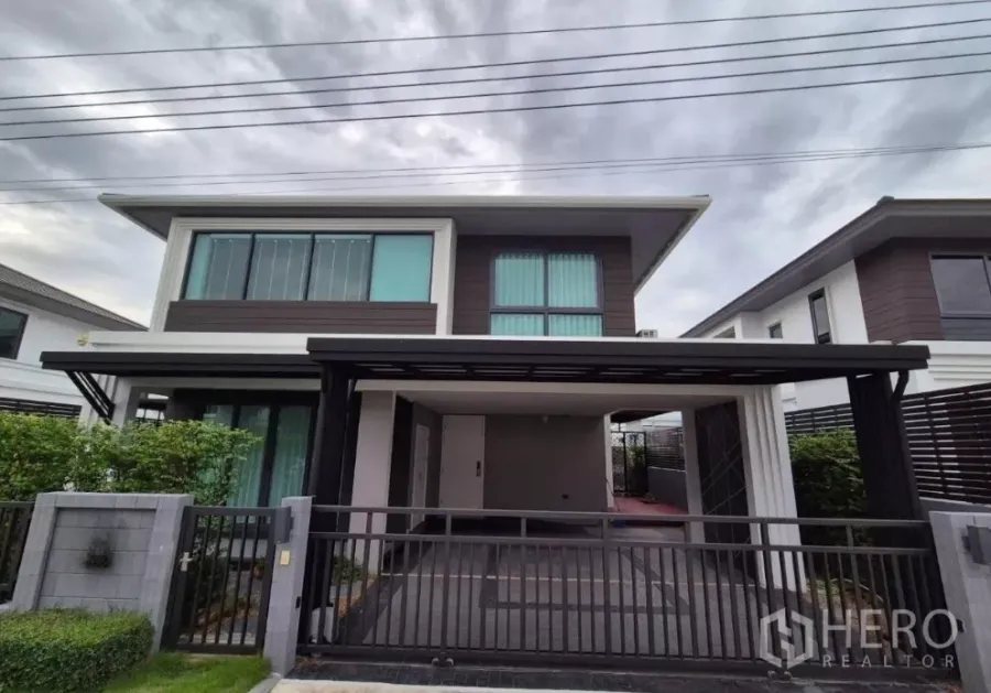 บ้าน ขายในBang Kruai, Nonthaburi - บ้านเดี่ยวสองชั้นด้านหน้า พร้อมโรงจอดรถ ประตูรั้ว และแนวไม้พุ่มในบางกรวย นนทบุรี