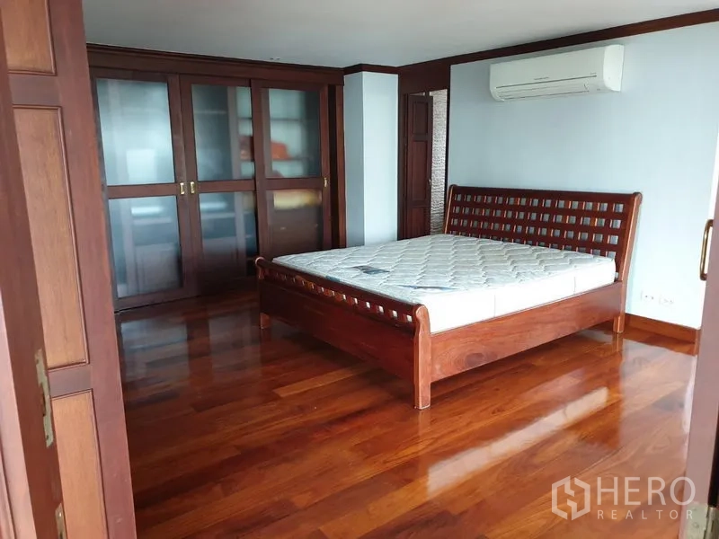 公寓 出租在Watthana, Bangkok - 宽敞卧室，实木床架，抛光木地板，带磨砂玻璃门的内嵌衣柜。