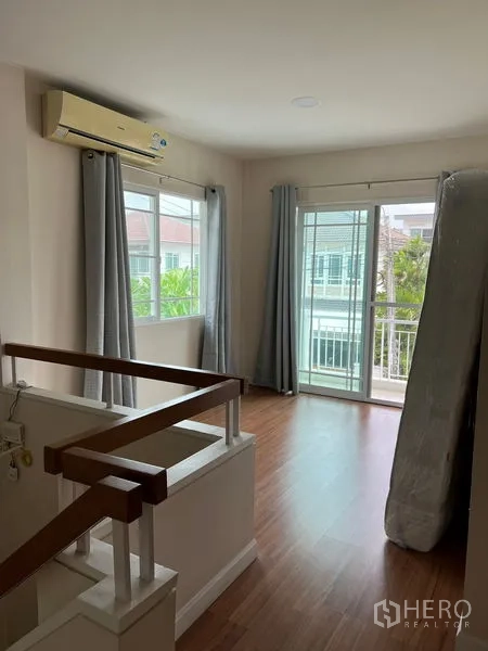 Detached House for rent in Bang Kapi, Bangkok - Upstairs landing with wood floors, windows, and sliding door to a small balcony.