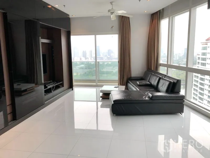 คอนโด ให้เช่าในKhlong Toei, Bangkok - ห้องนั่งเล่นชั้นสูง โซฟาหนังสีดำ พื้นกระเบื้องเงา หน้าต่างกระจกเต็มบานเห็นวิวสวนและเส้นขอบฟ้า