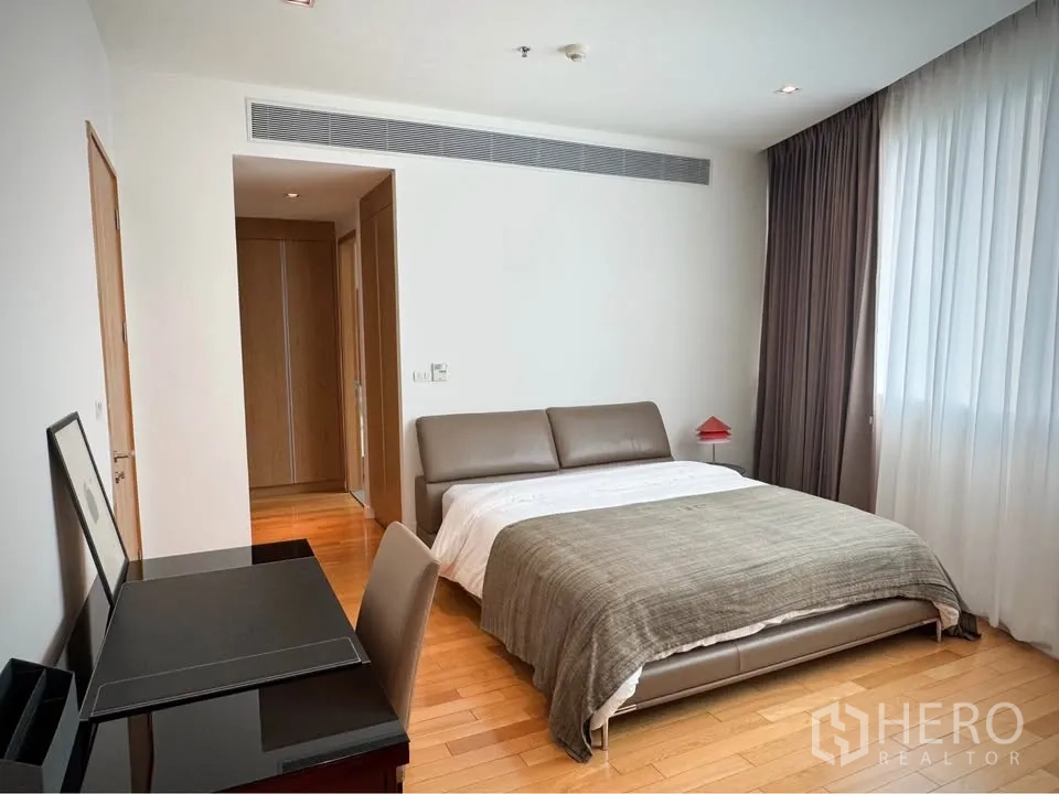 คอนโด for rent or sale in Khlong Toei, Bangkok - ห้องนอนหลักพร้อมเตียงบุนวม โต๊ะทำงาน และหน้าต่างกว้างพร้อมผ้าม่าน.