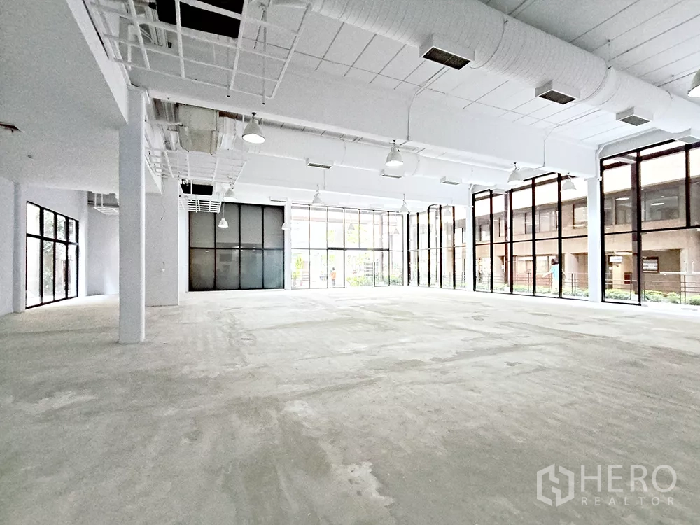 Office Space for rent in Watthana, Bangkok - Deep open office floorplate with ceiling ducts and glass doors opening to the walkway outside.