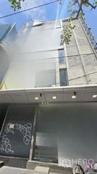 零售空间 出租在Watthana, Bangkok - 曼谷一栋中高层商业楼外观，金属立面与卷帘门，晴天街景。