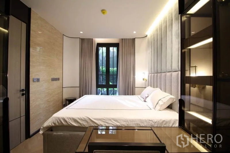 Condominium for rent in Watthana, Bangkok - Serene bedroom with padded headboard, double bed, tall window and built-in wardrobes.