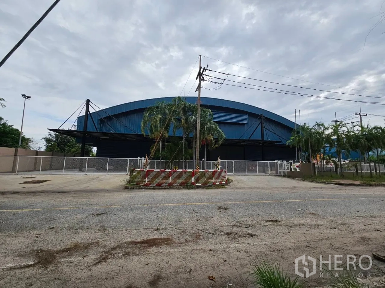 โรงงาน for rent in Si Racha, Chon Buri - มุมหน้าทางเข้าโรงงานหลังคาสีน้ำเงิน พร้อมรั้วล้อมรอบในศรีราชา