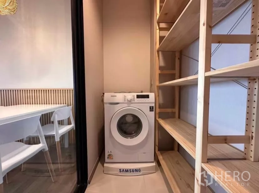 Condominium for rent in Chatuchak, Bangkok - Laundry closet with front-load washing machine and wooden storage shelves.