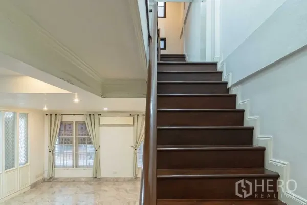 สำนักงานที่บ้าน ให้เช่าในBang Rak, Bangkok - ชั้นล่างปูพื้นลายหินอ่อน หน้าต่างบานใหญ่พร้อมผ้าม่าน และบันไดไม้สีเข้ม