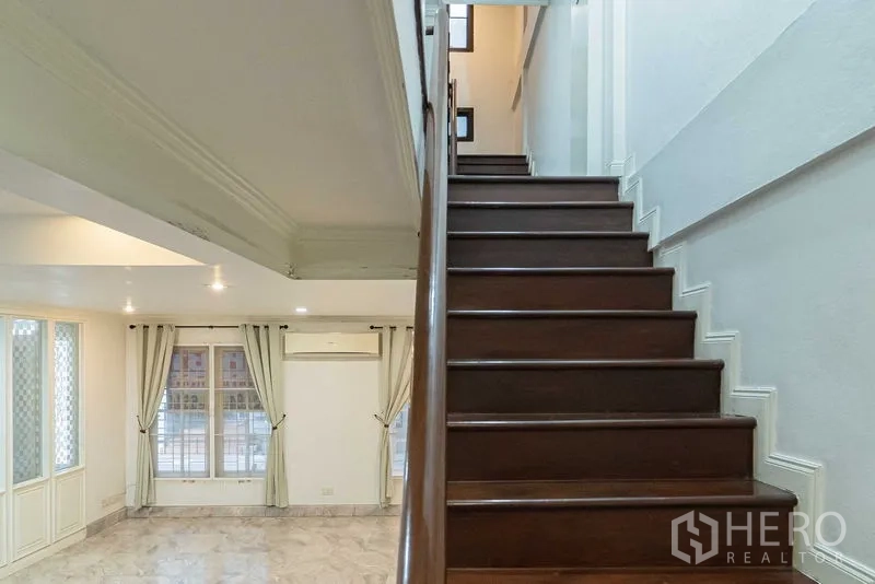 สำนักงานที่บ้าน ให้เช่าในBang Rak, Bangkok - ชั้นล่างปูพื้นลายหินอ่อน หน้าต่างบานใหญ่พร้อมผ้าม่าน และบันไดไม้สีเข้ม