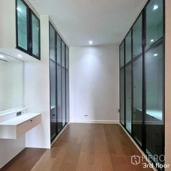 Detached House for rent in Bang Kapi, Bangkok - Dressing area with twin glass wardrobes and built-in vanity on wood flooring.