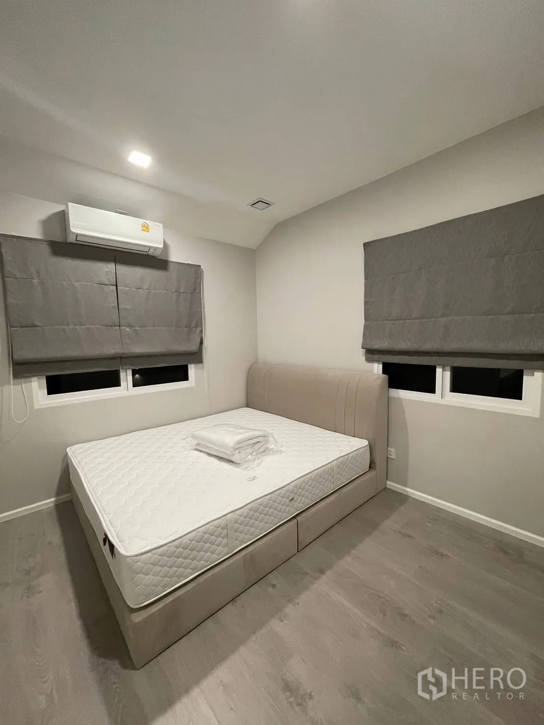 Detached House for rent in Prawet, Bangkok - Cozy bedroom with bed, air conditioner, and grey Roman blinds.