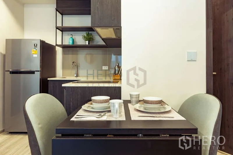 Condominium for rent or sale - Dining table set for two beside compact kitchen with open shelves.