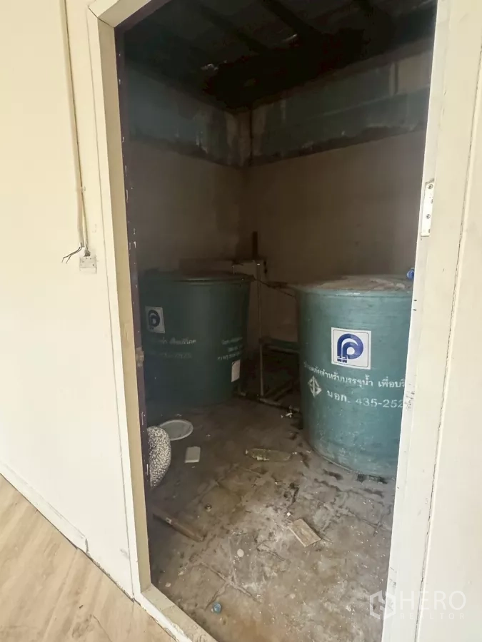 Shophouse for rent in Samphanthawong, Bangkok - Utility room containing large water storage tanks and unfinished floor.