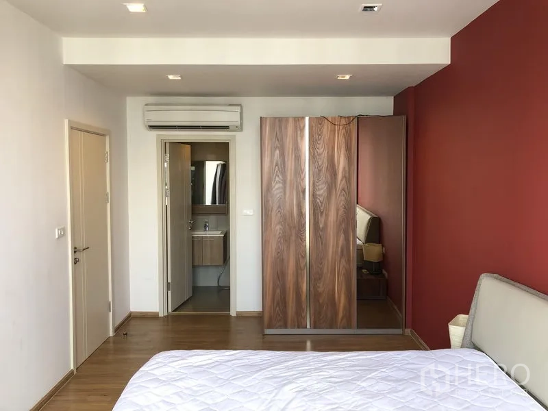 Condominium for rent in Watthana, Bangkok - Bedroom showing built-in wardrobe, air conditioning and doorway to an ensuite bathroom.