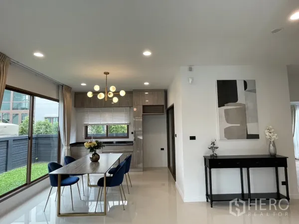 Detached House for rent in Bang Kapi, Bangkok - View from dining to kitchen with pendant light, glossy cabinets, and the yard outside.