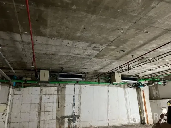 零售空间 出租 - 工业风天花特写，裸露管道、喷淋与空调设备于毛坯商铺内。