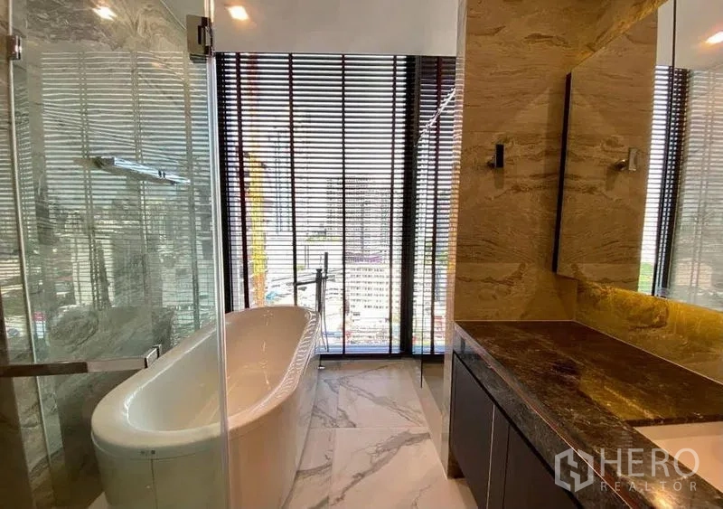 Condominium for rent in Watthana, Bangkok - Luxurious bathroom with freestanding bathtub, glass shower and marble vanity facing city views.