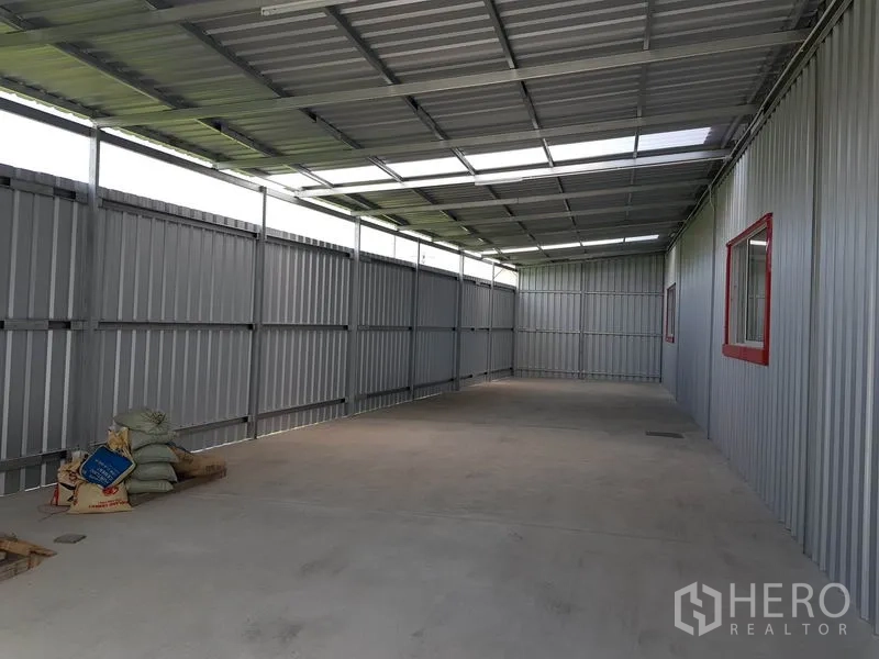 Warehouse for rent in Nonthaburi - Covered side bay with metal walls and roof, suitable for loading or auxiliary storage.