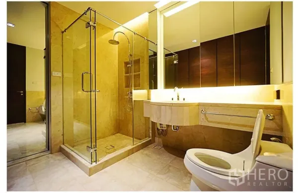 公寓 出售在Watthana, Bangkok - 现代浴室，玻璃围合雨淋花洒，背光洗手台与大镜面，米色石材装饰。