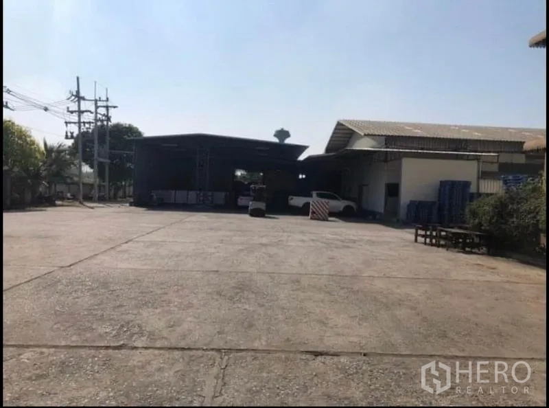 Factory for rent in Bang Khla, Chachoengsao - Broad concrete forecourt between factory buildings with power lines nearby.