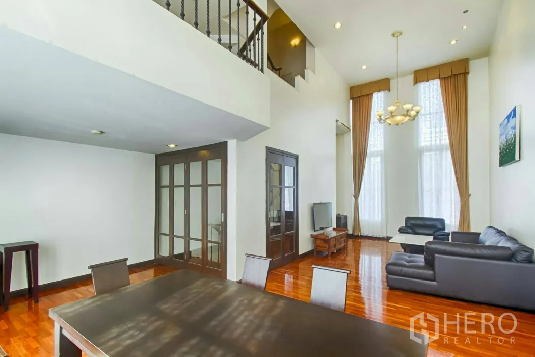 Townhouse for rent in Watthana, Bangkok - Open-plan lounge and dining area with mezzanine level and sliding glass doors.