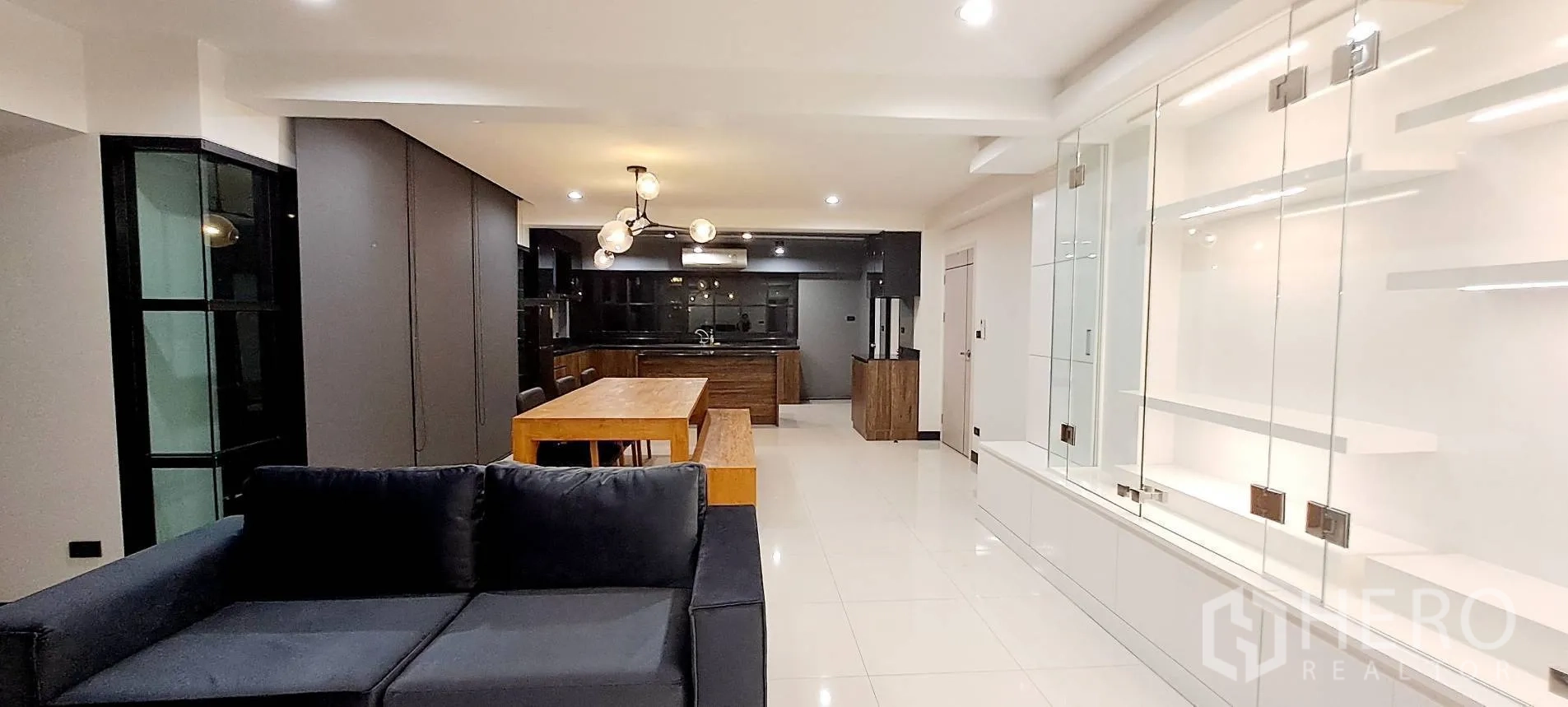 Apartment for rent in Phra Khanong, Bangkok - Open-plan living space with sofa, dining table, and island kitchen.