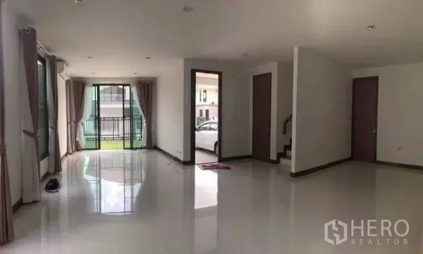 Detached House for rent or sale in Thanyaburi, Pathum Thani - Spacious ground-floor living area with sliding glass doors to the lawn, staircase and carport access.