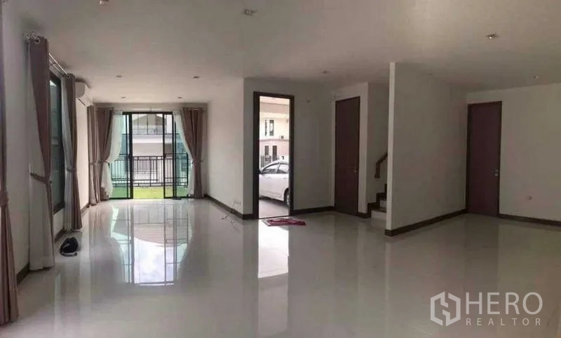 Detached House for rent or sale in Thanyaburi, Pathum Thani - Spacious ground-floor living area with sliding glass doors to the lawn, staircase and carport access.