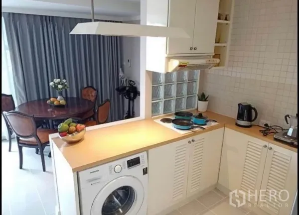 คอนโด ให้เช่าหรือขายในKhlong Toei, Bangkok - ครัวเปิดเคาน์เตอร์รูปตัวแอล มีเครื่องซักผ้า เตาไฟฟ้า และโต๊ะกินข้าวทรงกลมข้างผ้าม่านสูง