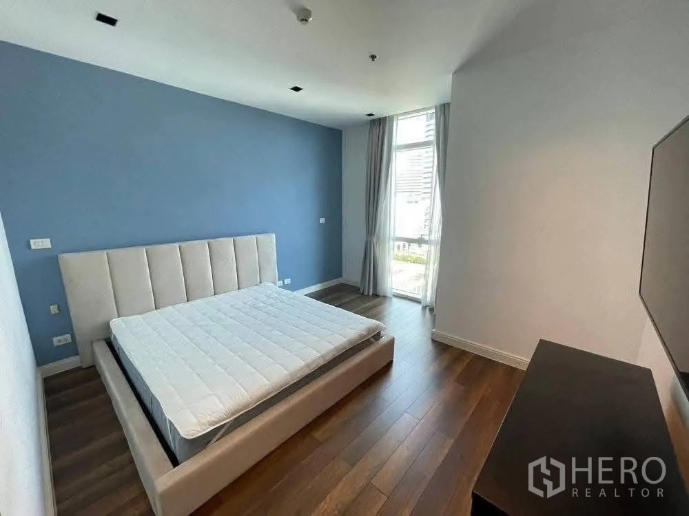 คอนโด for rent in Pathum Wan, Bangkok - ห้องนอนพร้อมเตียงบุผ้า พื้นไม้ และหน้าต่างสูงมองเห็นวิวเมือง