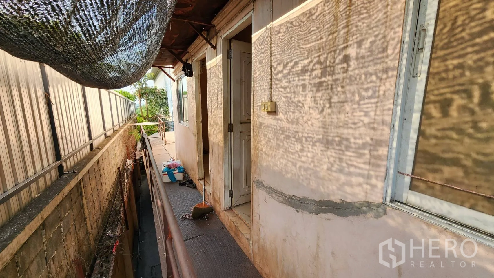 货栈 出租在Nonthaburi - 后侧服务走道，防晒网棚与围墙相邻。