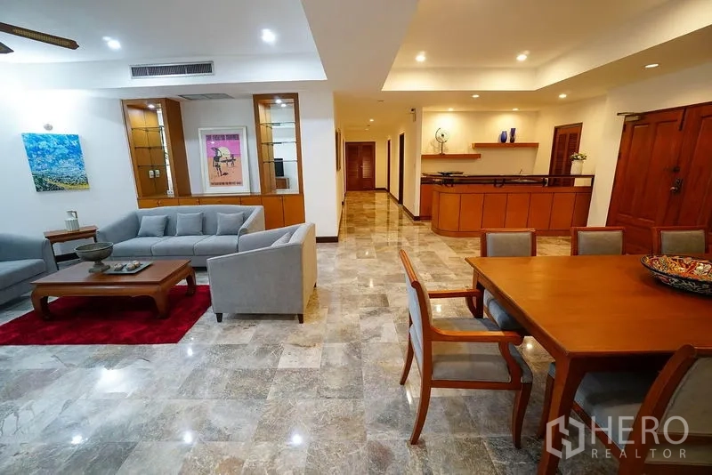 อพาร์ทเมนท์ ให้เช่าในWatthana, Bangkok - ห้องรับแขกสว่างด้วยโซฟาสีเทา งานศิลป์บนผนัง และมุมทานอาหารข้างเคาน์เตอร์บาร์บิวท์อิน.