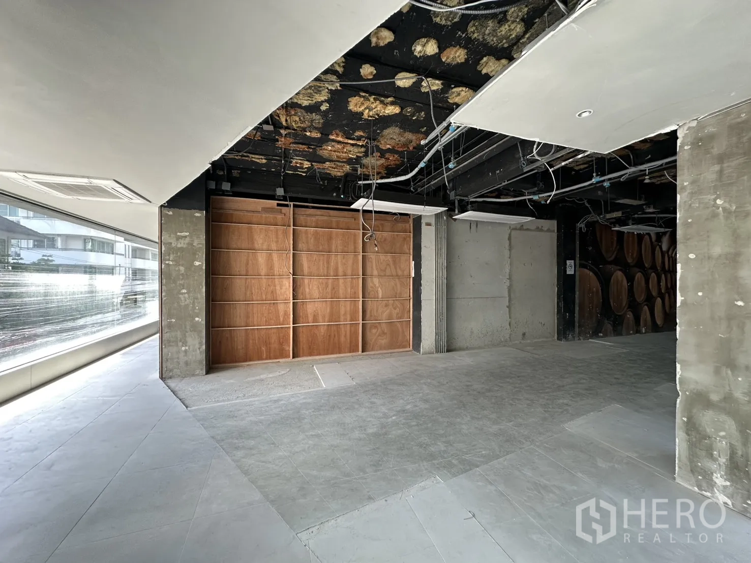 Retail Space for rent in Watthana, Bangkok - Open area with concrete columns, plywood display wall, and expansive glazing.