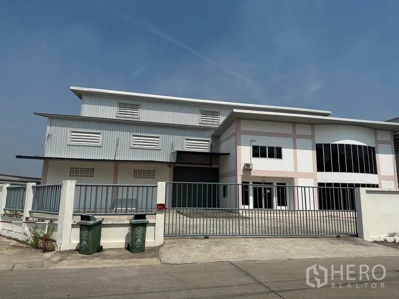 คลังสินค้า ให้เช่าในSamut Prakan - ด้านหน้าโกดังพร้อมประตูเลื่อน รั้ว และทางรถเข้า