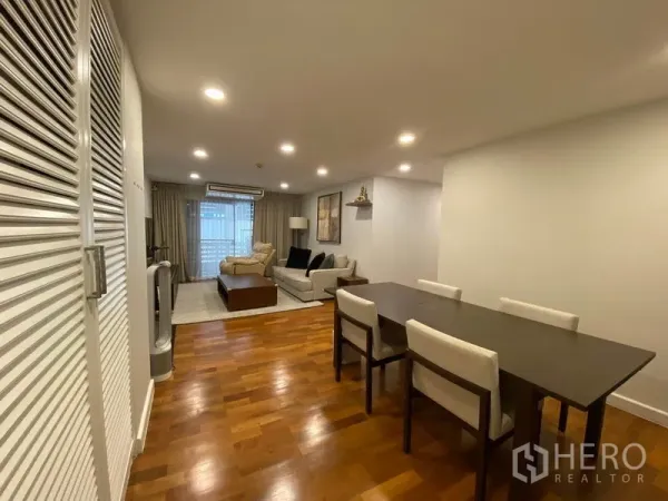 คอนโด ให้เช่าหรือขายในWatthana, Bangkok - โซนรับประทานอาหารและนั่งเล่นแบบโอเพ่นแปลน โต๊ะยาว ไฟดาวน์ไลท์ และประตูกระจกออกระเบียง